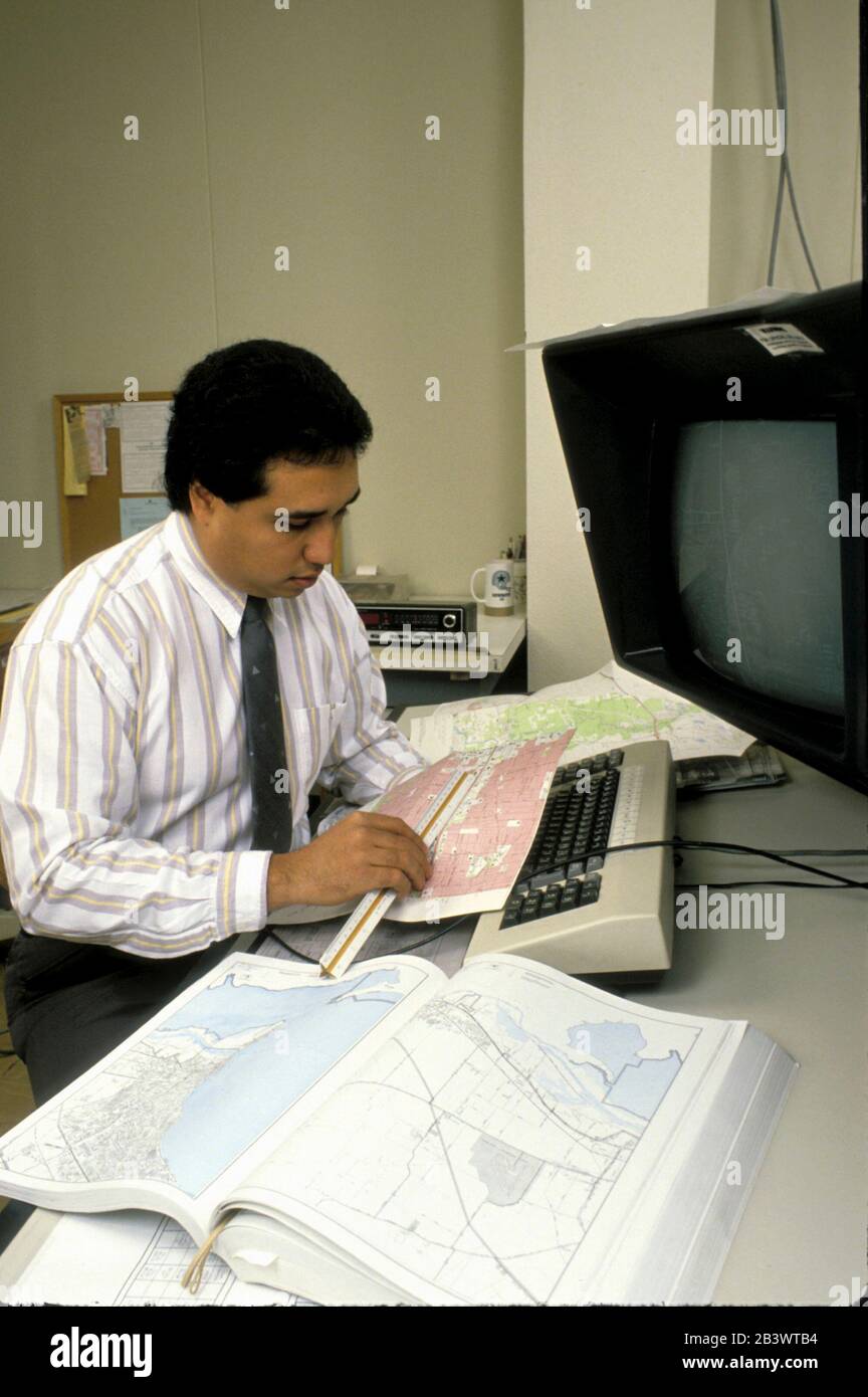 Austin Texas USA: Hispanic cartographer looks over maps in his office at the Texas Department of Transportation. ©Bob Daemmrich Stock Photo