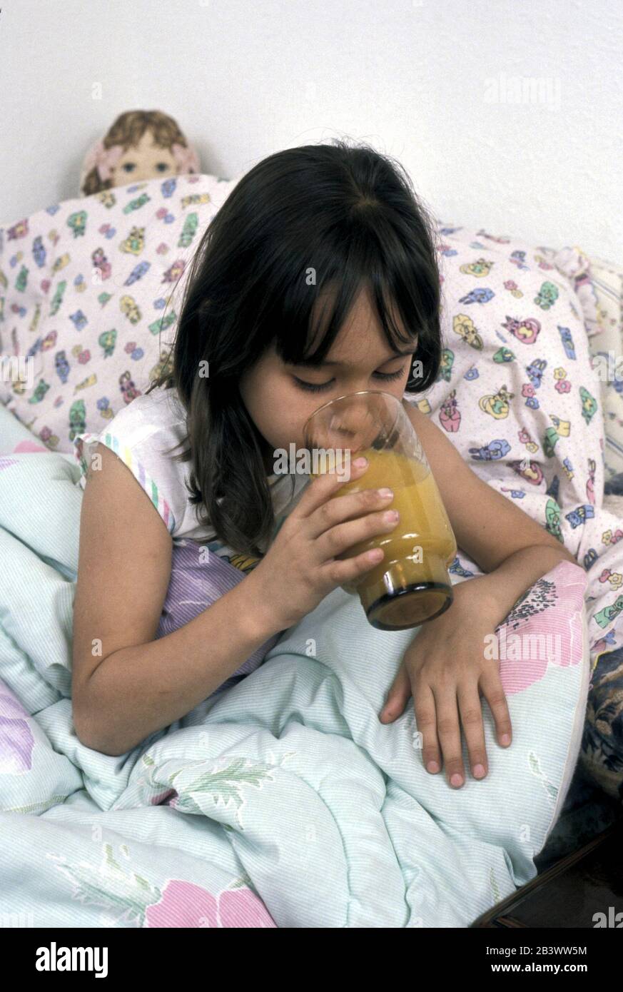 Austin, Texas USA: seven-year-old girl suffering from a mild cold drinking a glass of orange juice in bed before going to sleep. ©Bob Daemmrich Stock Photo