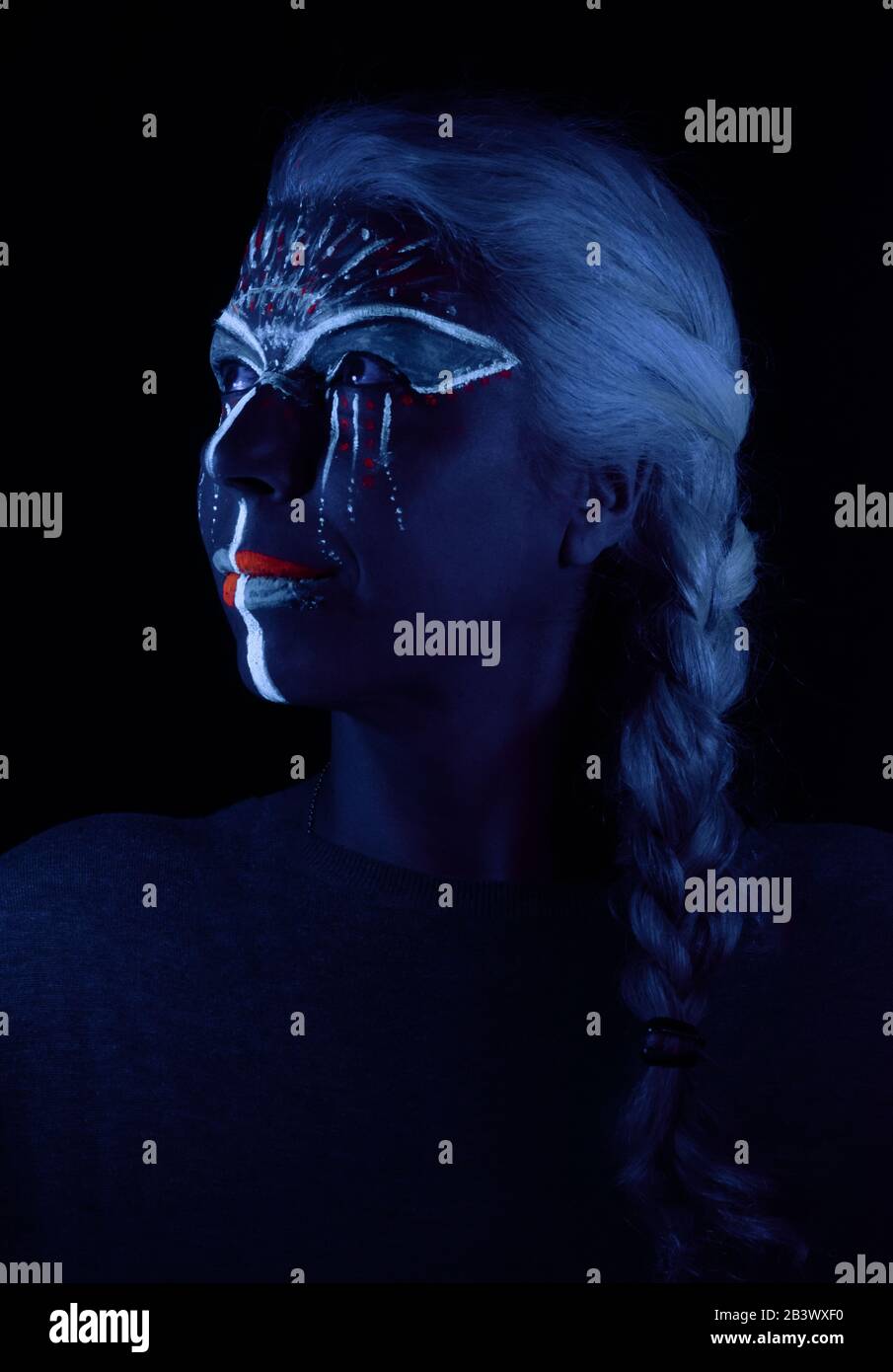 creative portrait of woman with white hair and ultraviolet face paint and black light Stock Photo