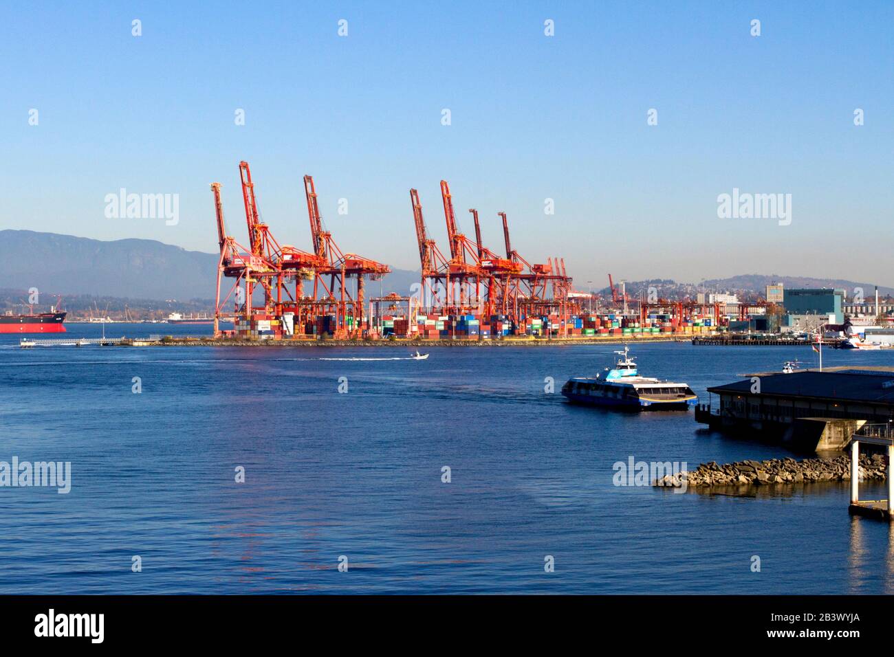 Gantry cranes at Port Metro Vancouver container terminal in the Burrard Inlet,Vancouver, BC, Canada and the SeaBus arriving at the Waterfront terminal Stock Photo