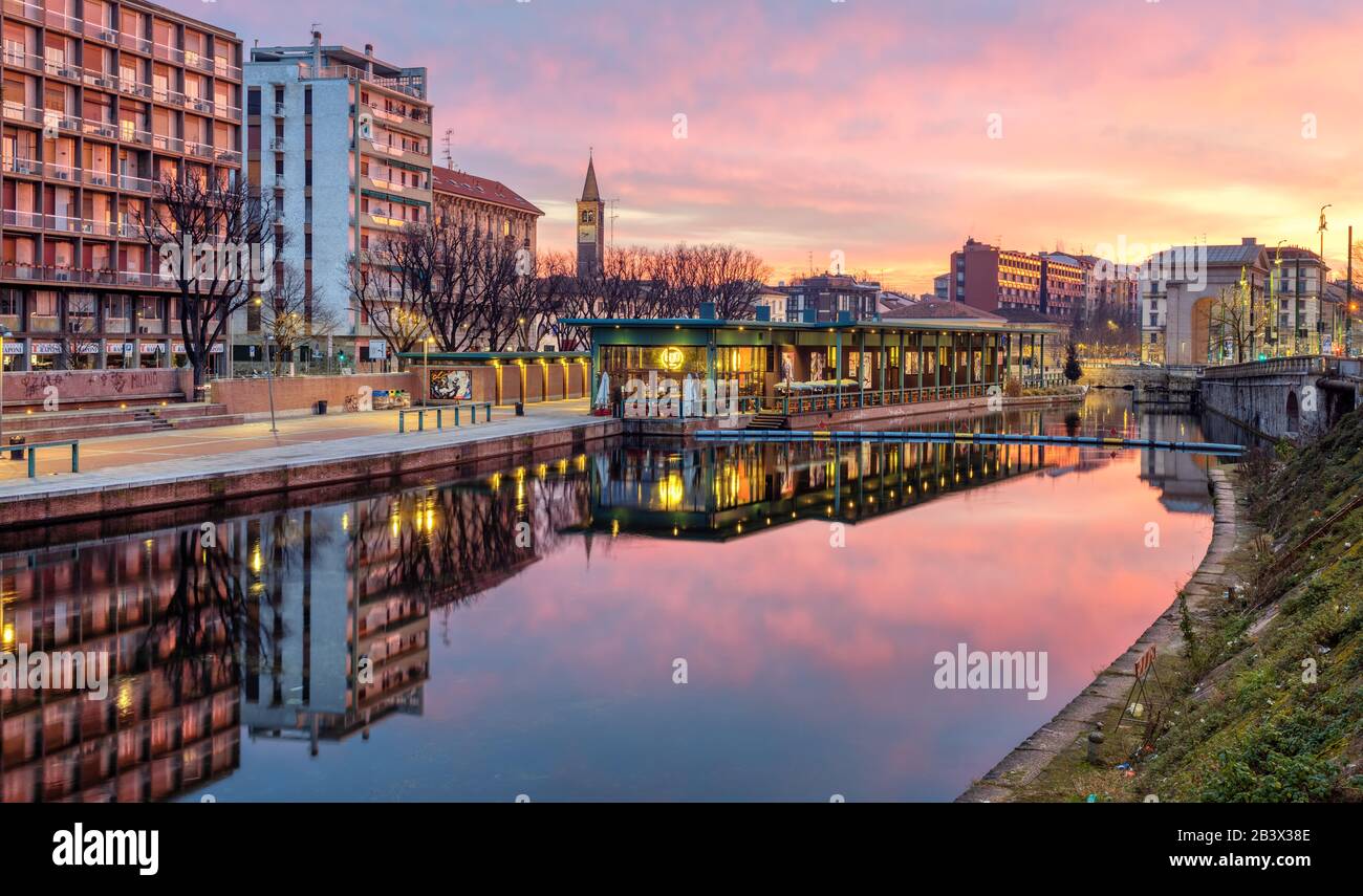 Milan, Italy - 10 February 2020: Porta Ticinese quarter in Milan town center reflecting in Darsena del Naviglio canal on dramatic sunrise. This city a Stock Photo