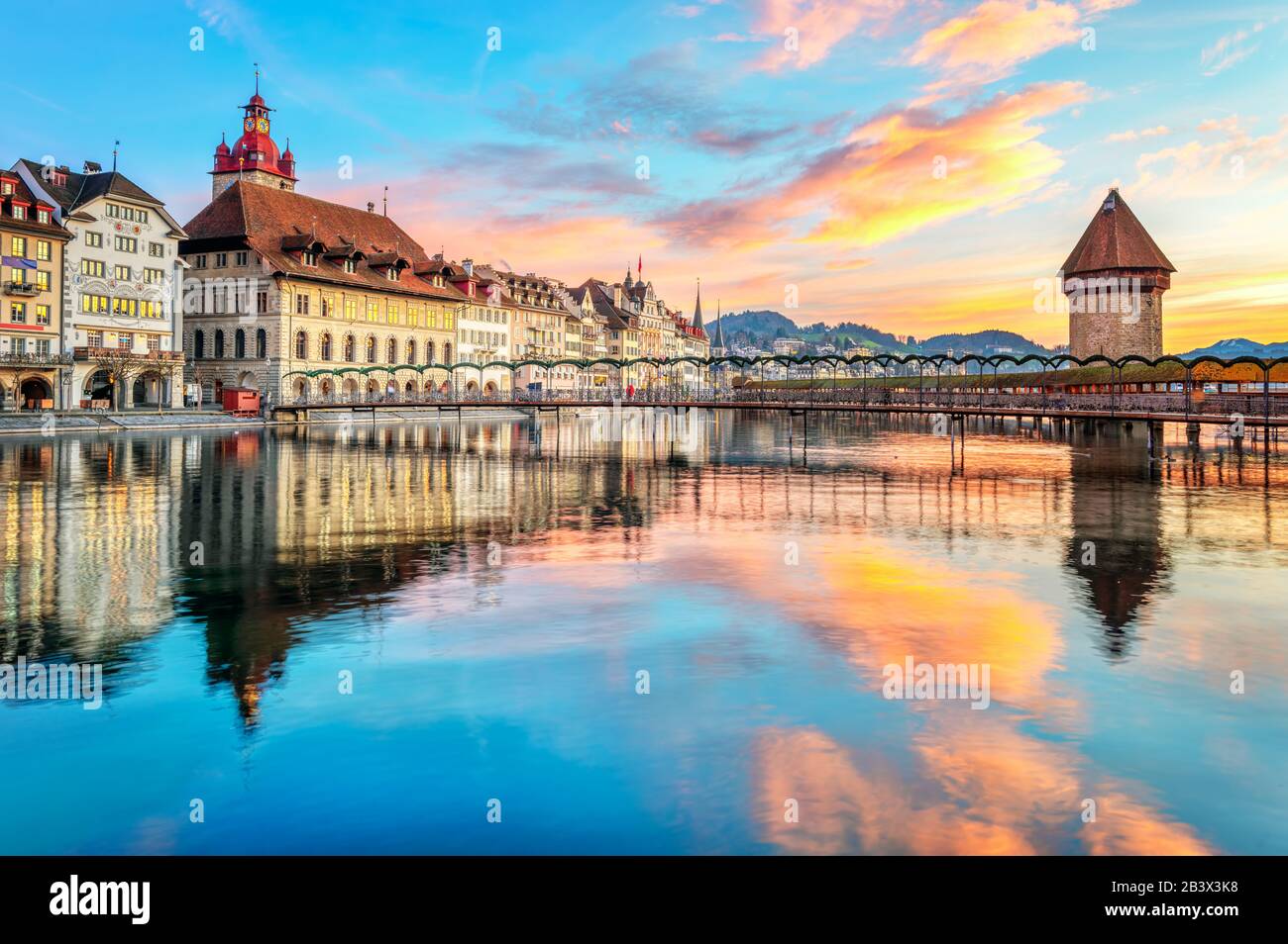 Historical wooden Chapel bridge and the Old town of Lucerne, Switzerland, reflecting in Reuss river on dramatical sunrise Stock Photo
