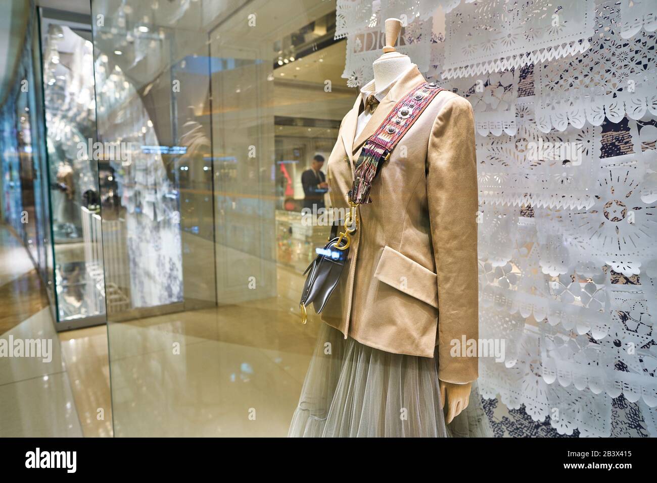 Shoppers reflected in a Dior window display near a Gucci store at