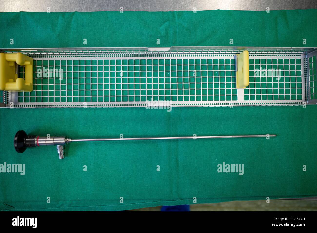 an endoscopic camera lies on a green surgical drape next to a tray