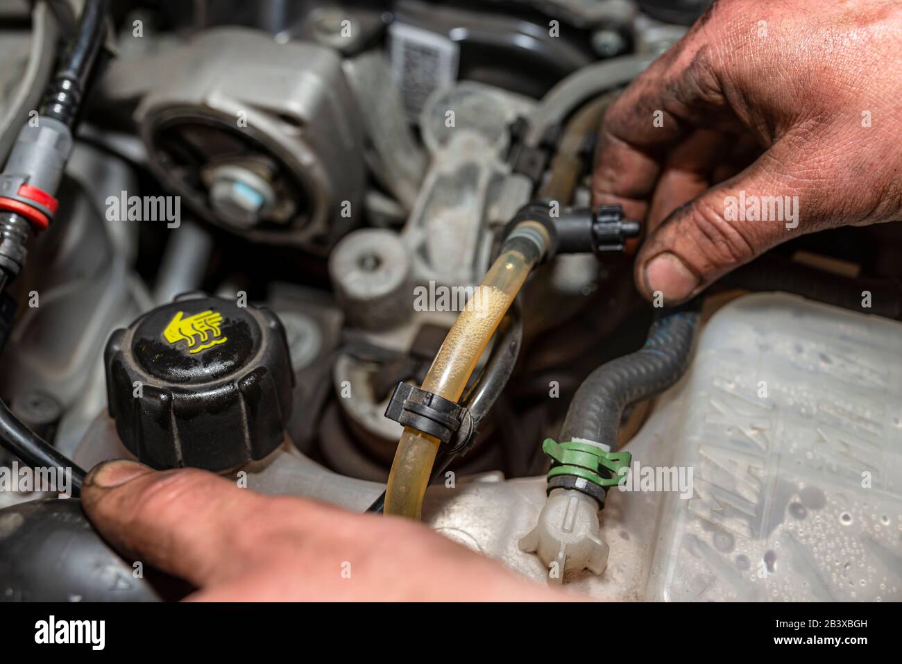 The mechanic bleeds the fuel system with a pump that is on the fuel line, after installing a new fuel filter, the man hands are visible. Stock Photo