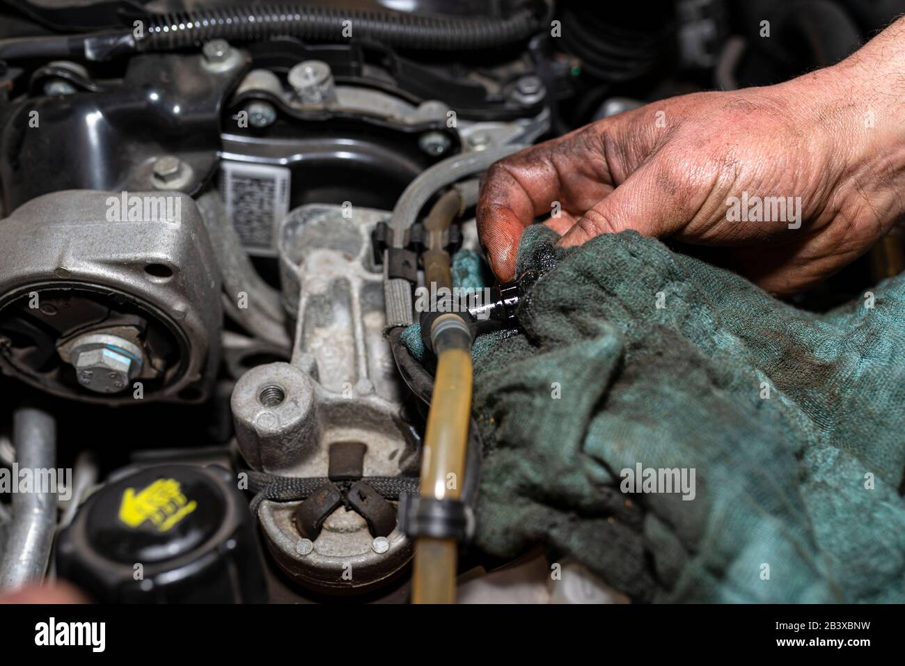 The mechanic bleeds the fuel system with a pump that is on the fuel line, after installing a new fuel filter, the man hands are visible. Stock Photo