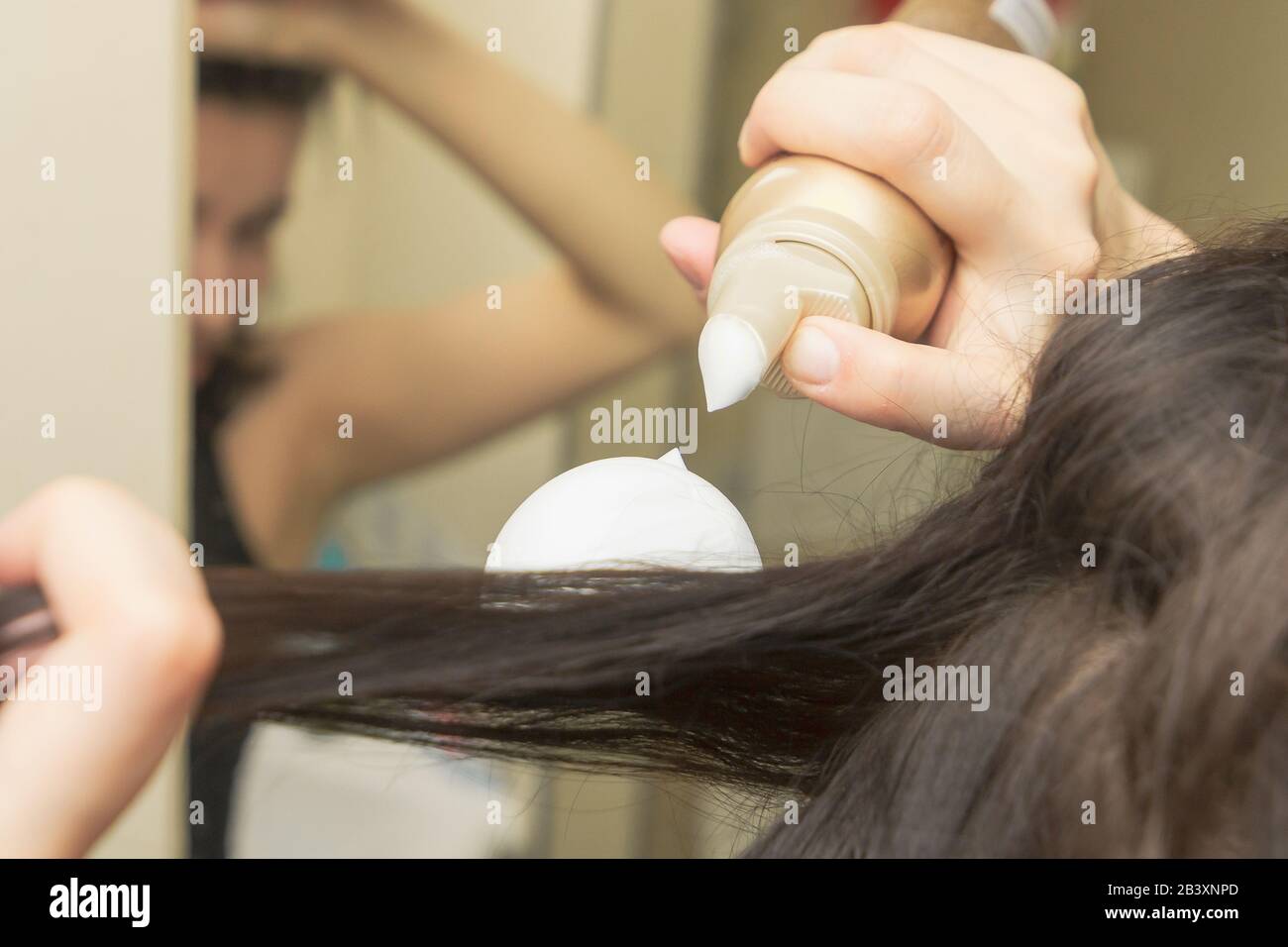Young women is styling her hair with a foam or mousse. Styling mousse on  the brown long straight hair Stock Photo - Alamy