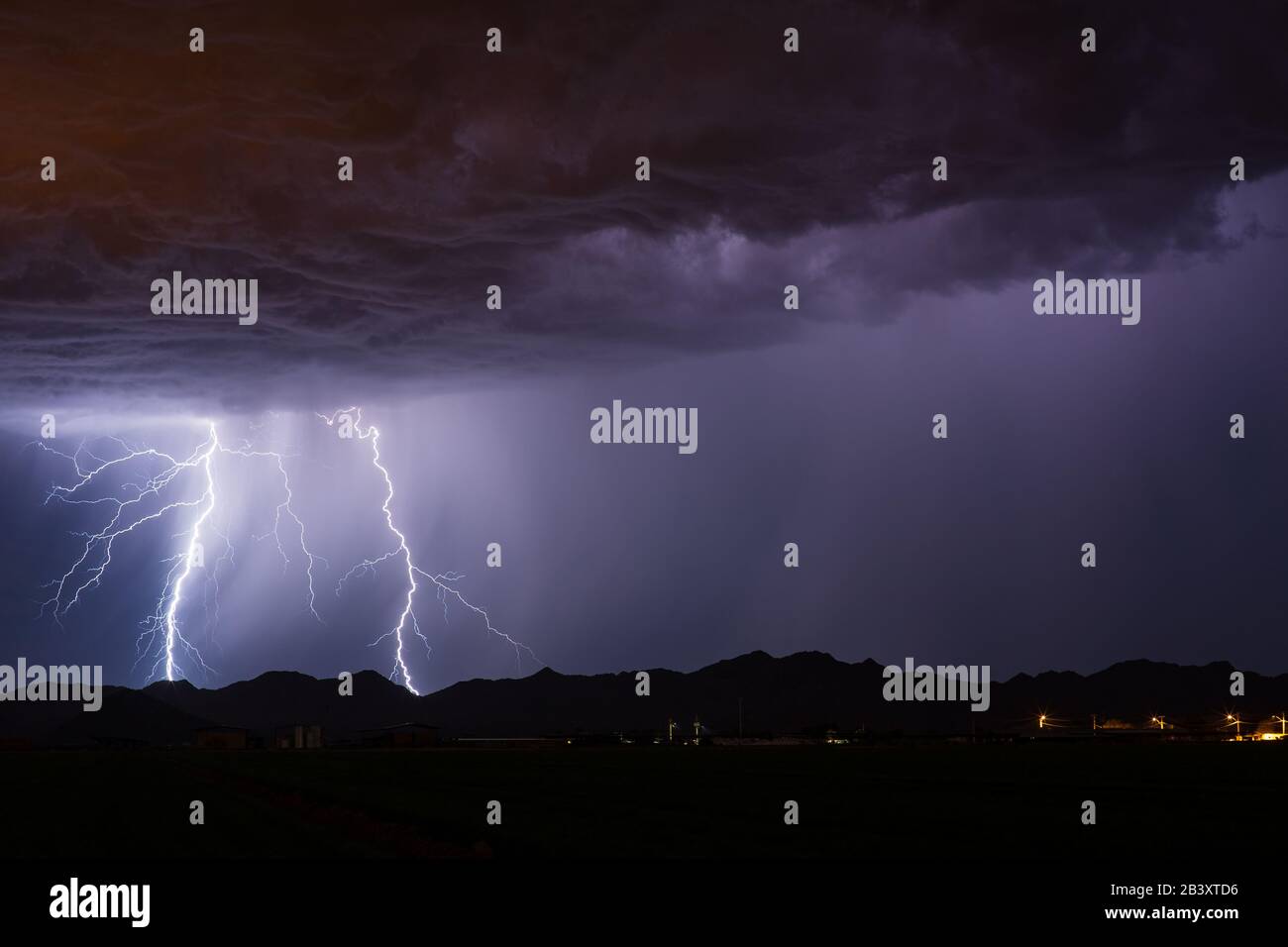 A lightning strike hitting a mountain as a strong monsoon thunderstorm moves through Buckeye, Arizona Stock Photo