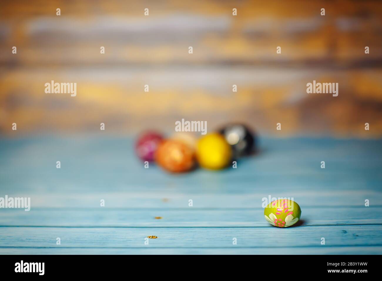 Easter colored painted small egg on blue and brown blurry wooden background with copyspace Stock Photo