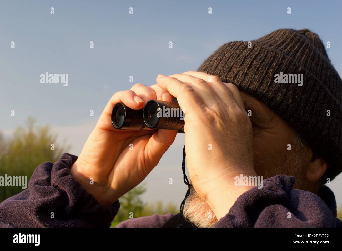 60 Year Old Man, Birdwatching with Binoculars on a Sunny Spring Day