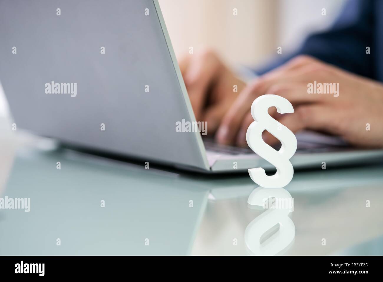 Businessperson's Hand Using Laptop With Paragraph Symbol On Desk Stock Photo