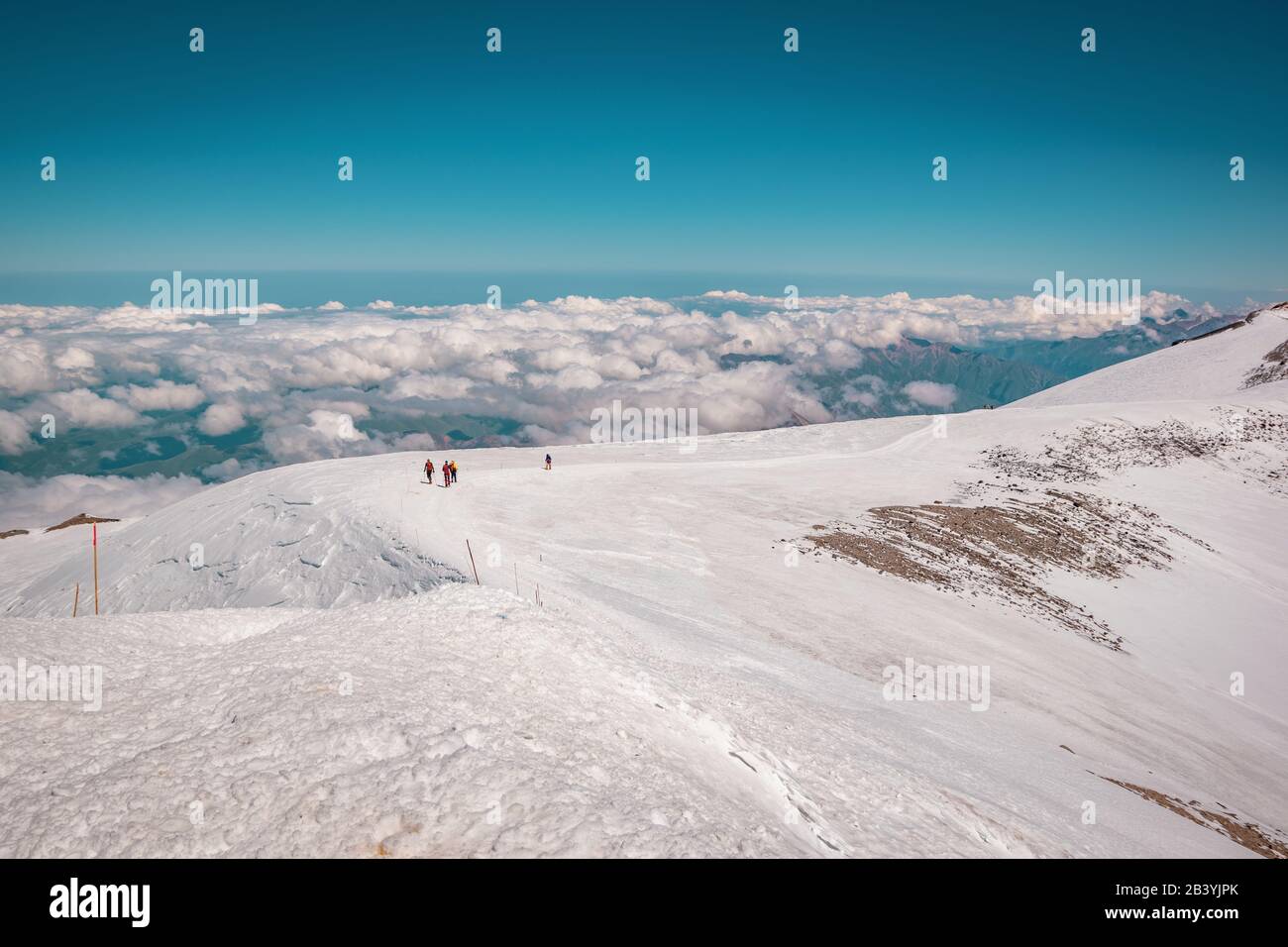 Landscape view of snow-capped hillside Mount Elbrus, Caucasus, Russia. A path leading down from the top. Group of alpinists descending from the top. Stock Photo