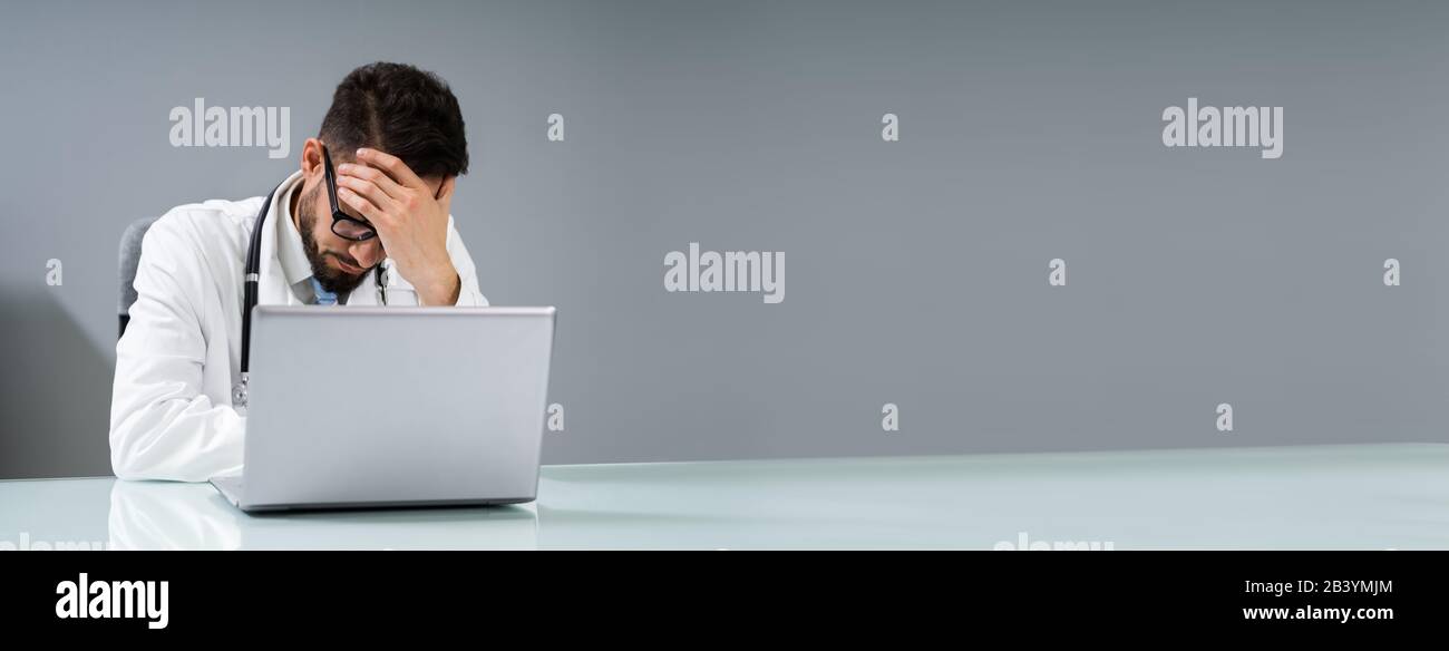 Sad Young Male Doctor Sitting In Clinic Stock Photo