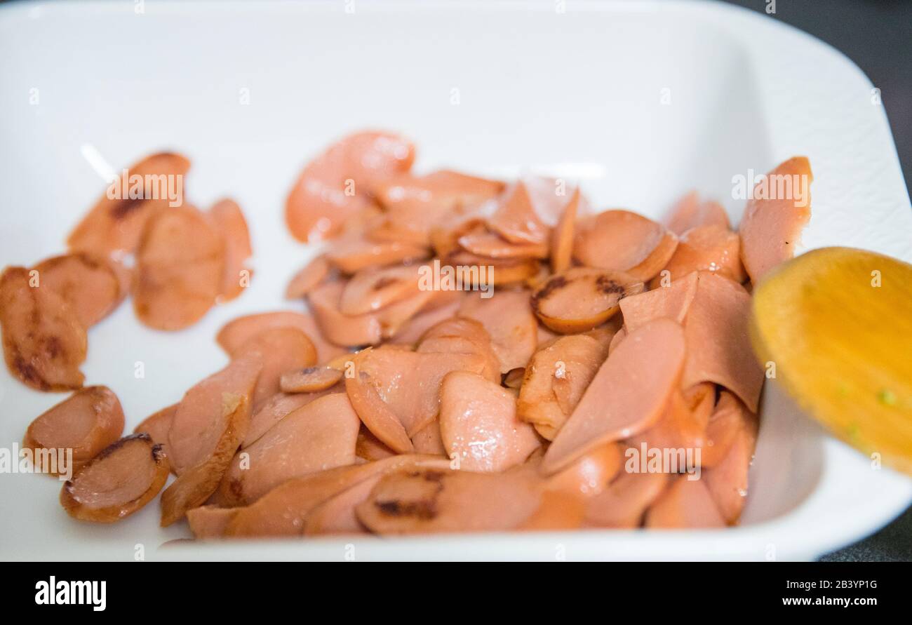 sliced sausages fried  in a black pan on the wooden table. Stock Photo