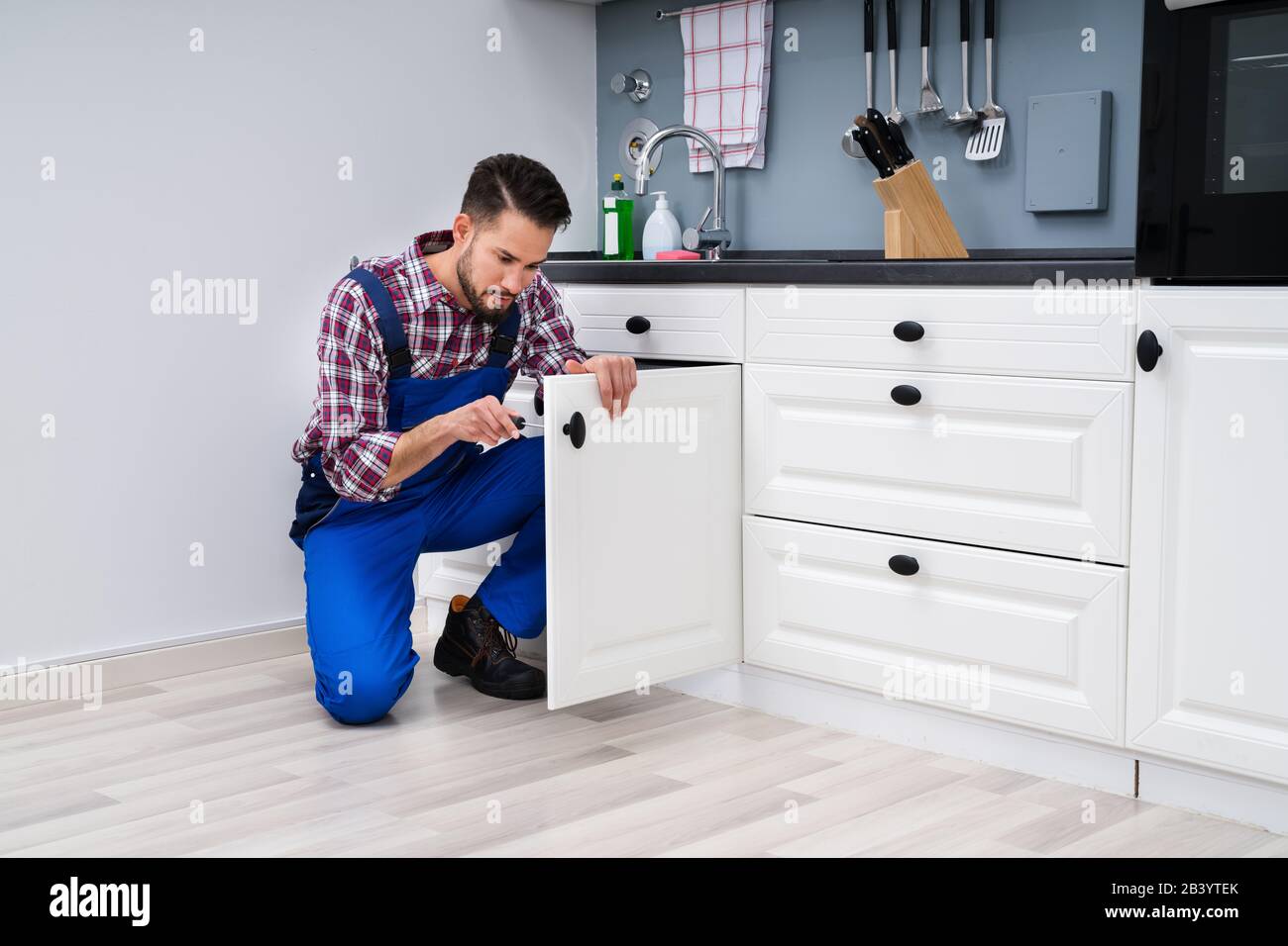 Young Handyman Fixing Sink Door In Kitchen Stock Photo - Alamy