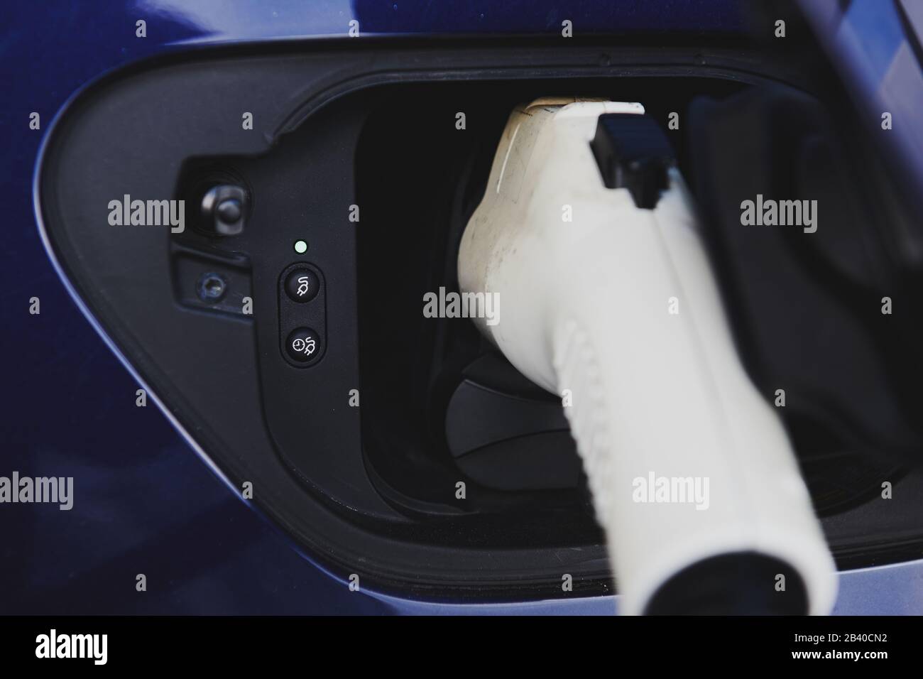 White plugin connector in blue electric car. Car while charging