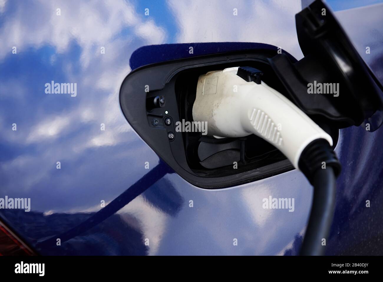 White plugin connector in blue electric car. Car while charging