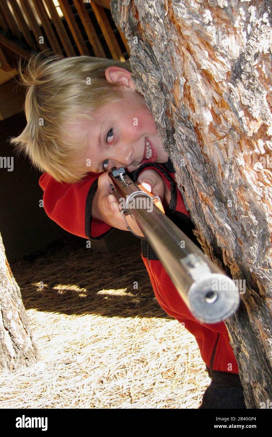 A young boy smiles while eyeing up his target with his BB gun. Stock Photo