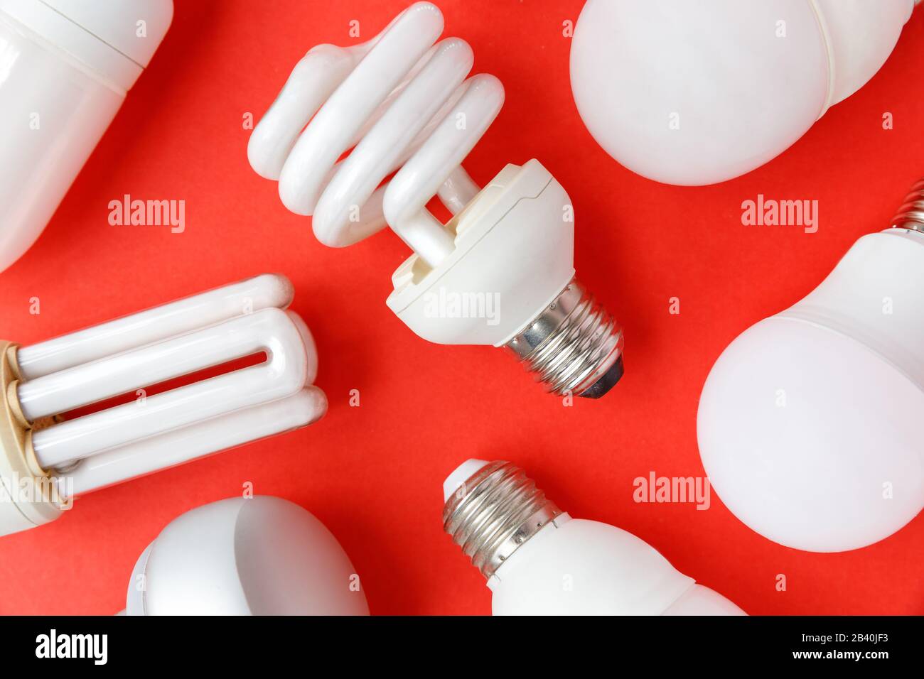 Spent incandescent halogen, cfi fluorescent, led, lumens light and energy saving bulbs tube, red background. Lamps containing mercury - extremely haza Stock Photo