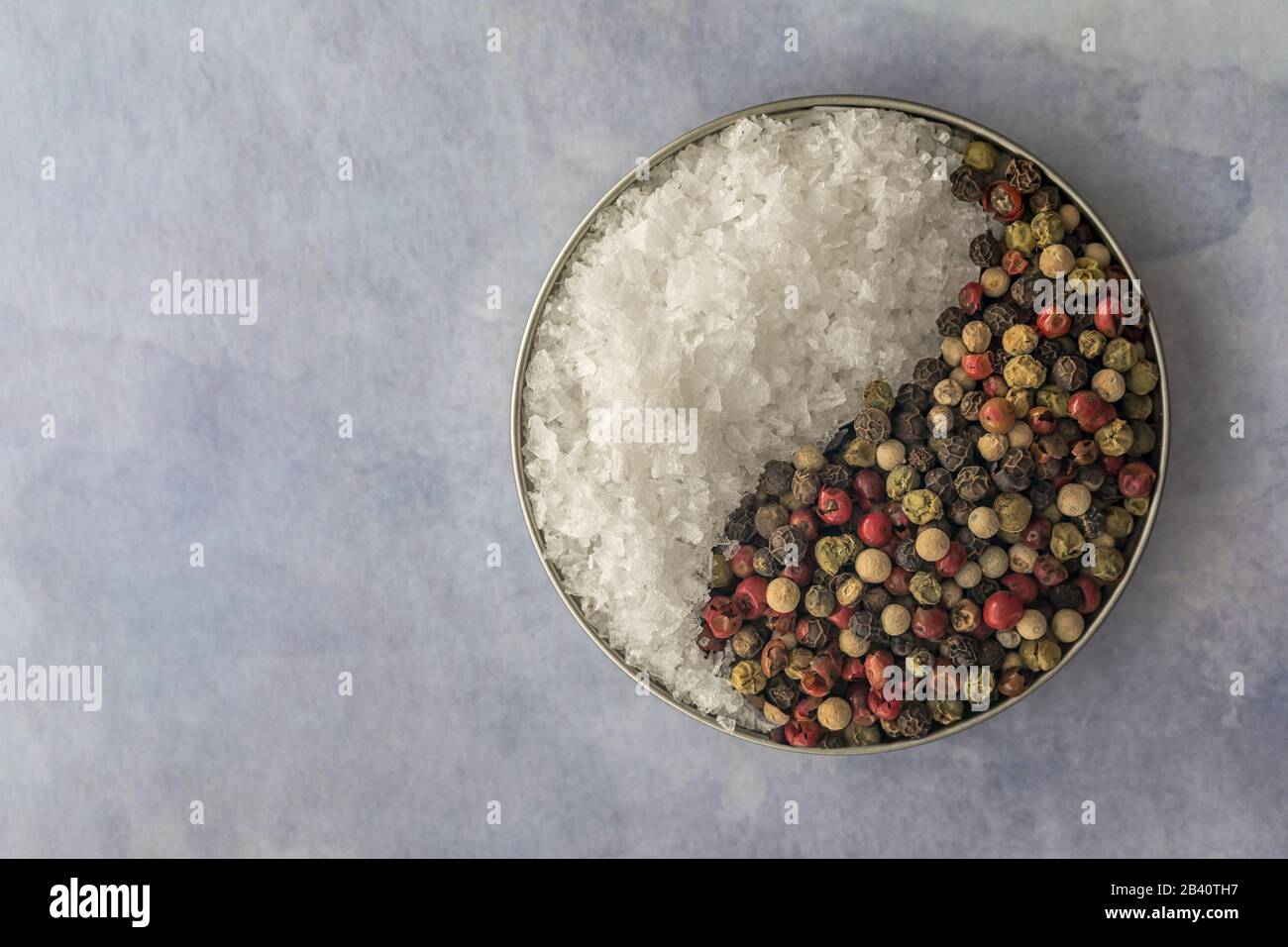 Sea Salt and Peppercorn seasoning; yin and yang of seasoning for cooking on a blue background Stock Photo