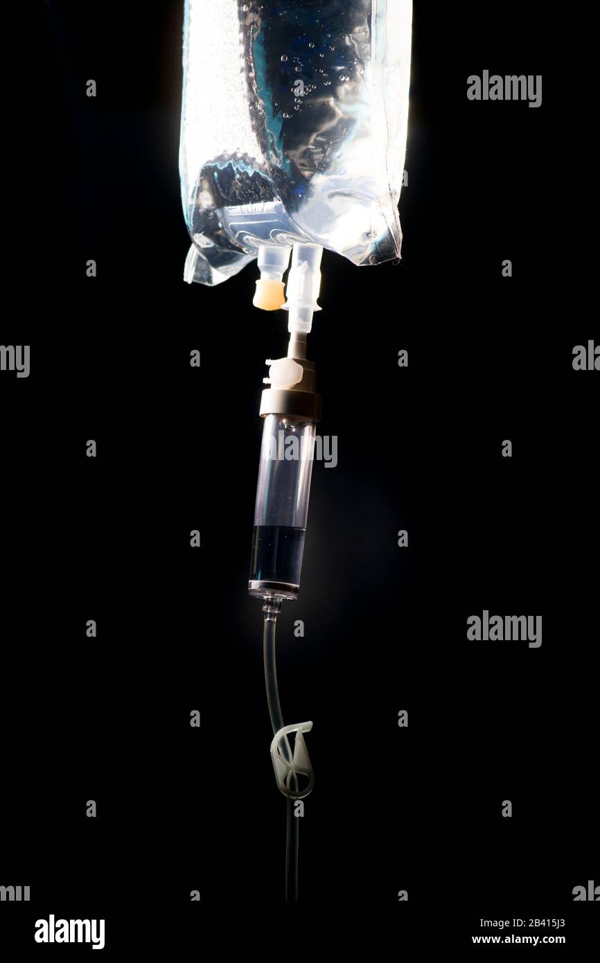 IV bag with IV tubing, clamp, and drip chamberon dark background. Stock Photo