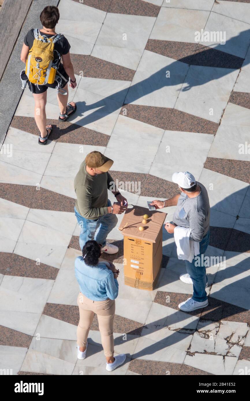 Aerial view of people betting money on the pea game, or three shell con. Man handing over a 20 euro note Stock Photo