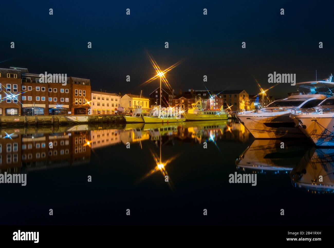 Bright street lights cast star shapes and reflections in the still waters of Poole Quay Stock