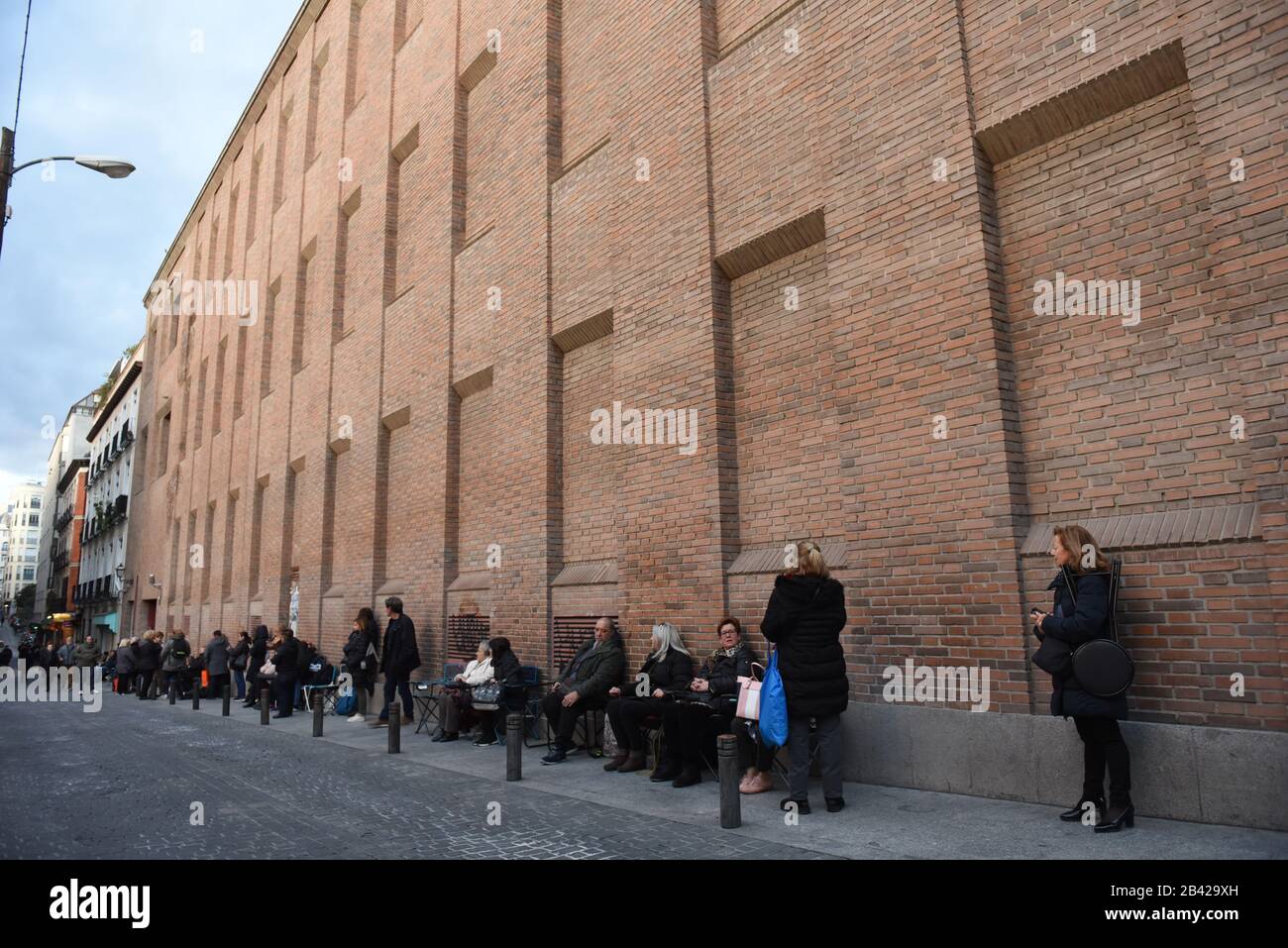 Believers wait in a queue on a street next to the Jesús de Medinaceli church in Madrid.Hundreds of Catholics from various countries gathered close to the  'Jesús de Medinaceli' church in Madrid on the first Friday of March, Friday of Lent,  to kiss the right foot of a 17th-century wooden image of Christ, known as Christ of Medinaceli. Pilgrims make three wishes to Jesus, of which he is said to grant one. However and because of the coronavirus, the church has forbidden believers to kiss him. Only one Mass will be celebrated. Stock Photo