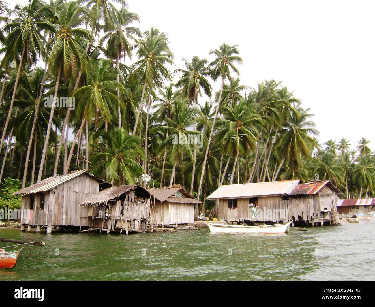 Fishing village with  houses on stilts along coconut groves in Surigao del Sur, Philippines Stock Photo