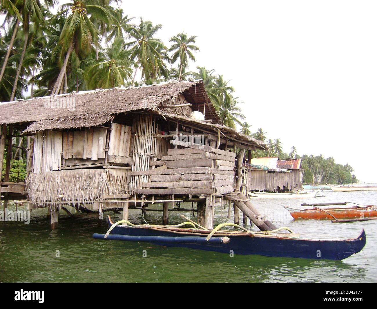 Medium close up of a houses on stilts with boats outside in a fishing village in Surigao del Sur, Philippines Stock Photo