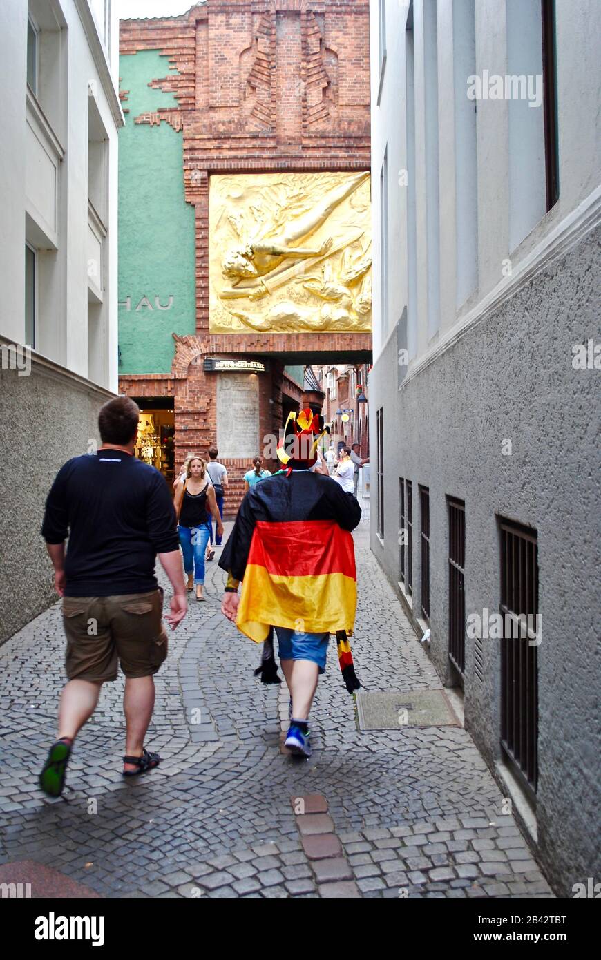 German Fussball (soccer or football) fan walks down Böttcherstrasse (Cooper's Alley) during World Cup. Lichtbringer ('Bringer of Light') by Hoetger Stock Photo