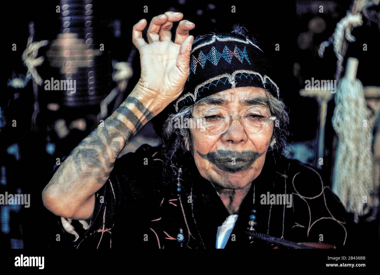 An elderly Ainu woman on the island of Hokkaido in northern Japan shows off tattooing that resembles a mustache around her mouth and encircles her arm. The painful tradition of rubbing soot into cuts in her skin was done during a girl's childhood to ward off evil spirits and to indicate she was qualified for marriage. The practice stopped more than a century ago after being outlawed by the Japanese government. The woman was one of only 300 pure-blooded Ainu still living when she posed for this historical photograph in 1962. Stock Photo