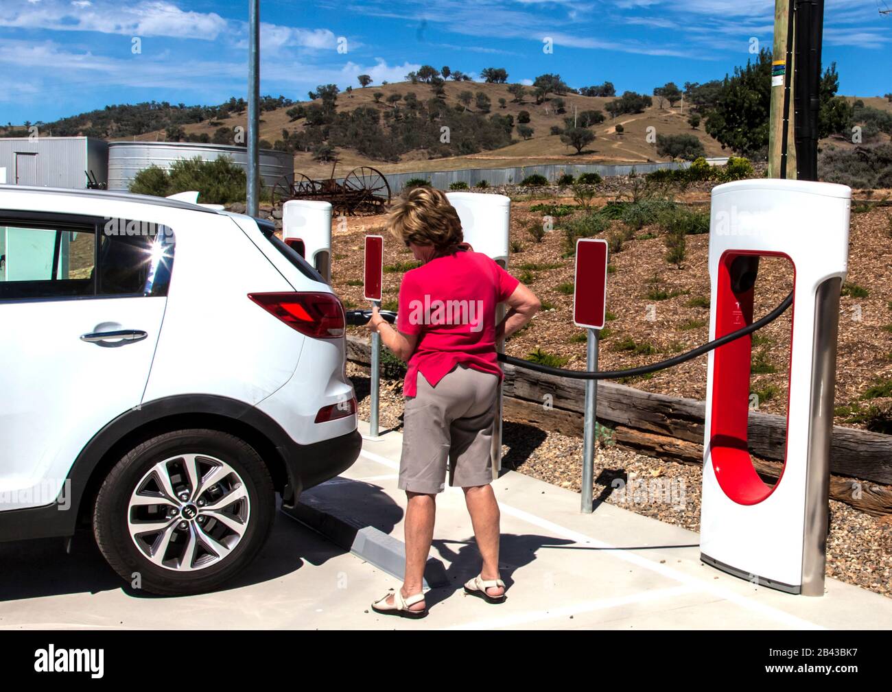 Woman motorist preparing to charge electric vehicle battery at Gundagai in Australian state of New South Wales Stock Photo