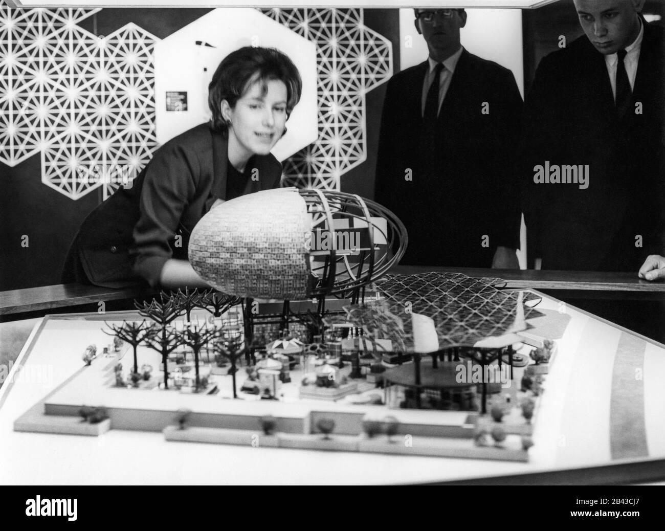 People viewing an architectural design model of the IBM pavilion with man-made steel trees and Ovoid Theater, designed by Charles Eames and Eero Saarinen for the 1964 New York World's Fair. The pavilion model was likely on display at the IBM Business Show in Manhattan at the New York Coliseum, circa April 30,1963. Stock Photo