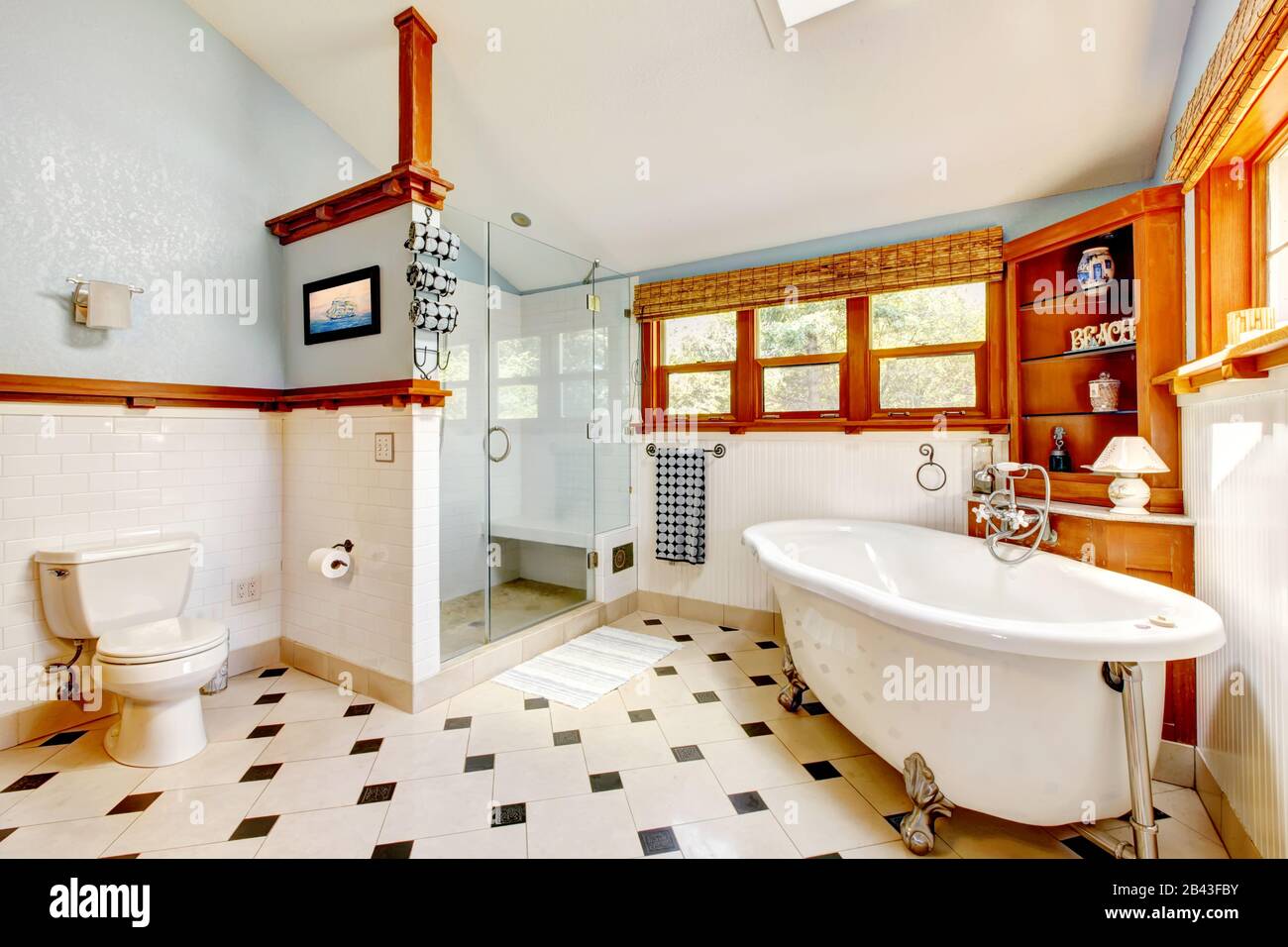Large classic blue bathroom interior with tub and tiles and wood cabinets. Stock Photo