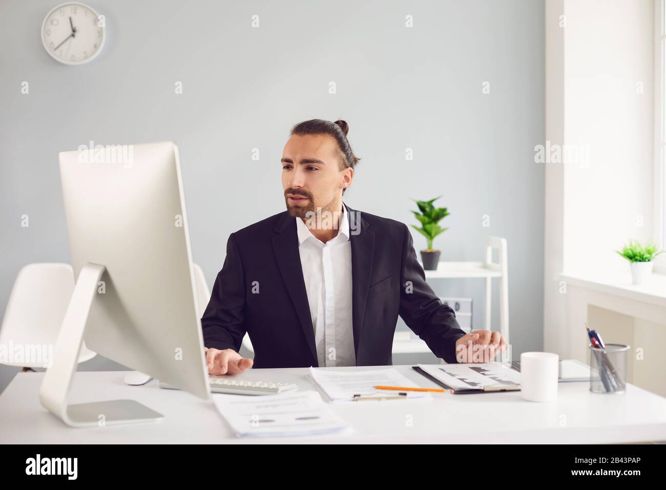 Businessman in a black jacket works. Analyzes at the computer in the office. Stock Photo