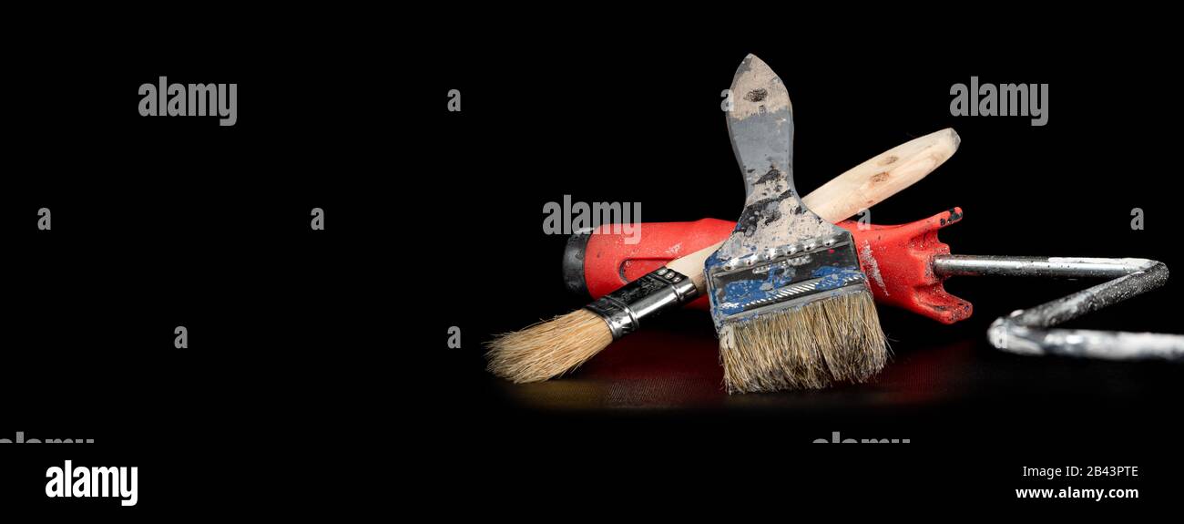 A paint brush and roller against a black background shot under studio lighting Stock Photo