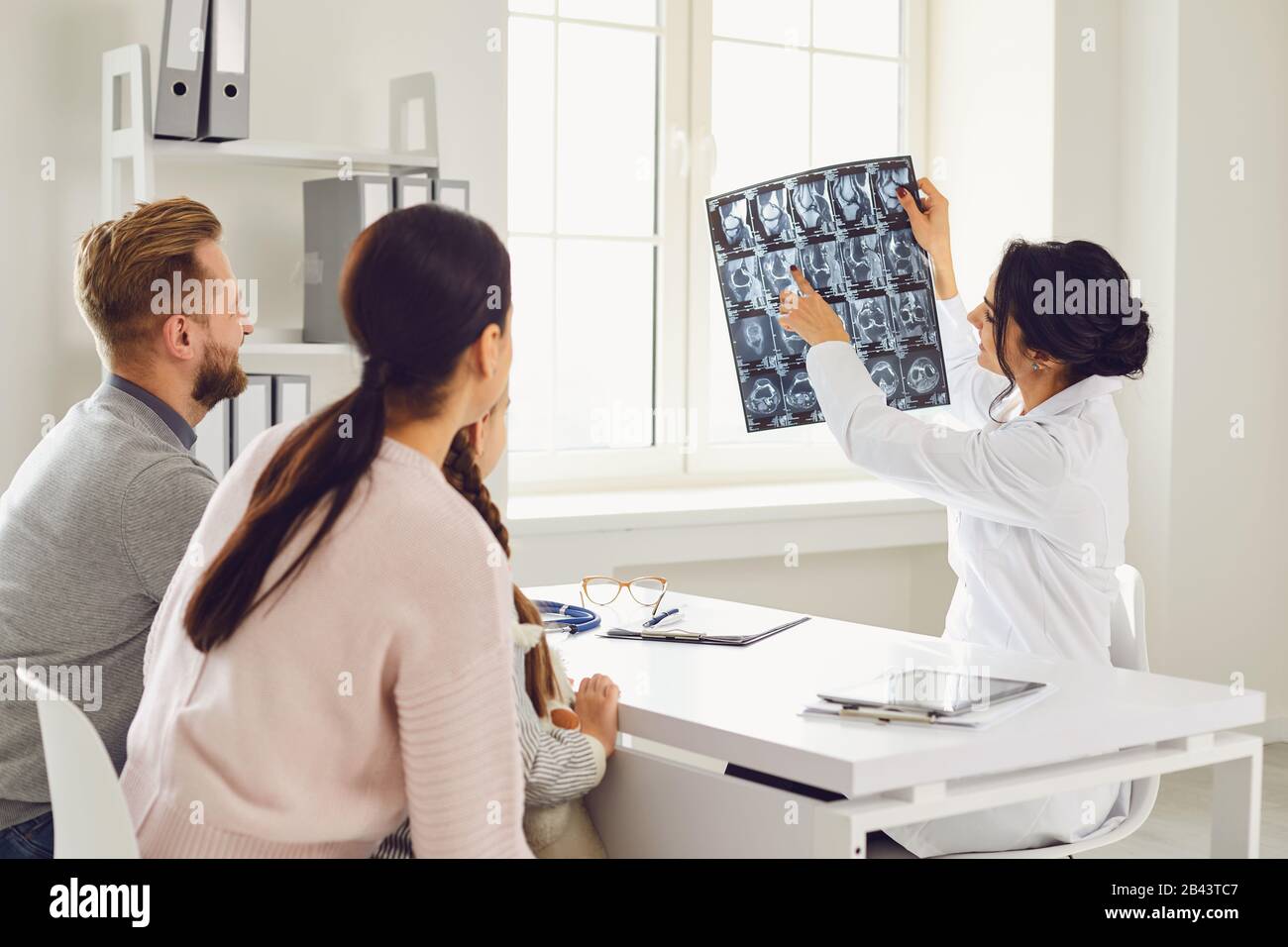 A family visiting a doctor shows x-ray sitting at a table in the room. Stock Photo