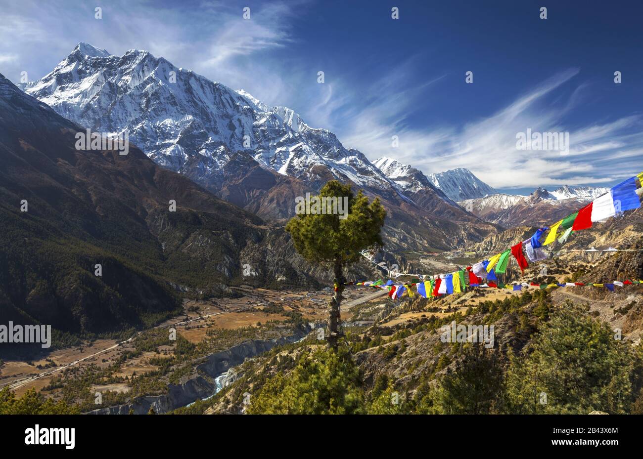 Himalaya Mountain Peak Range Landscape Scenic Skyline View, Buddhist Prayer Flags and Isolated Tree on Annapurna Circuit Trekking Hike Route in Nepal Stock Photo