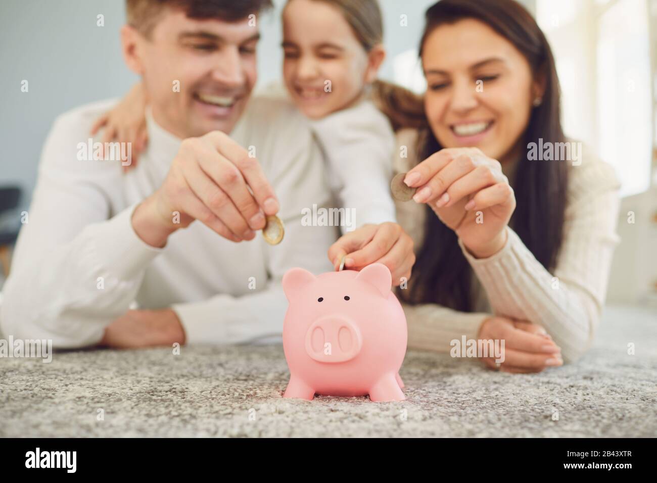 Happy family saves money in a piggy bank pig Stock Photo - Alamy