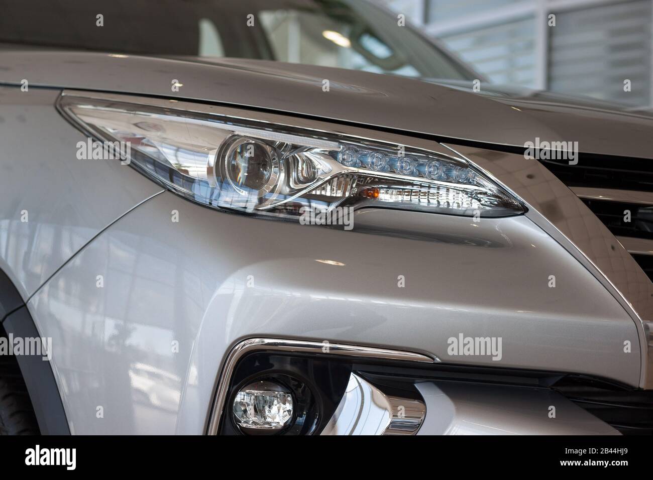 New modern vehicle with elegant head lamps in showroom. Side view. Stock Photo