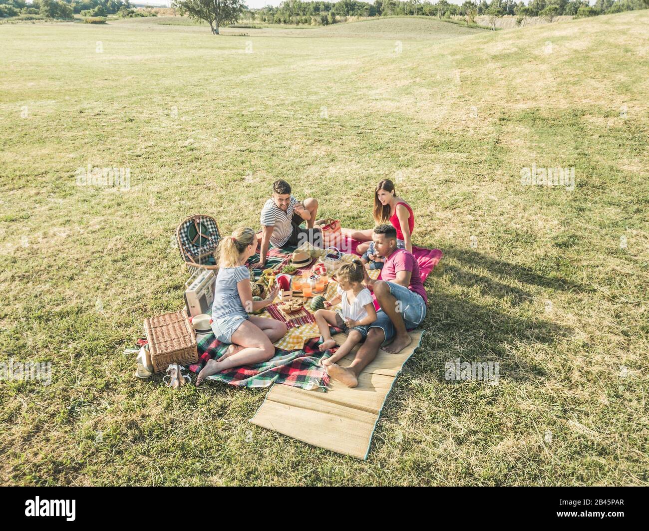 Happy Families Doing Picnic In Park Outdoor Young Parents Having Fun Happy Families Doing Picnic In Park Outdoor Young Parents Having Fun