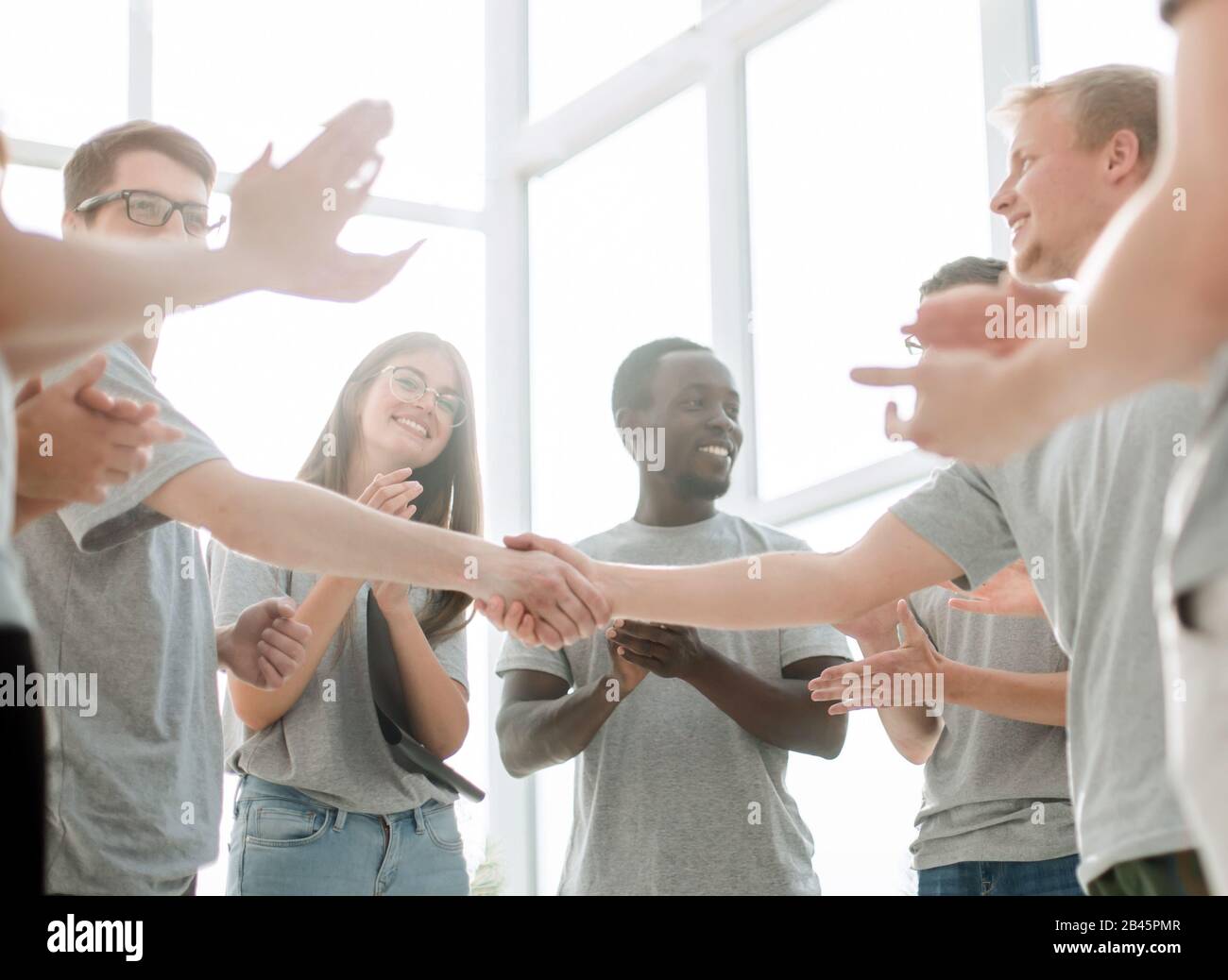 young people shaking hands, standing in a circle of friends Stock Photo ...