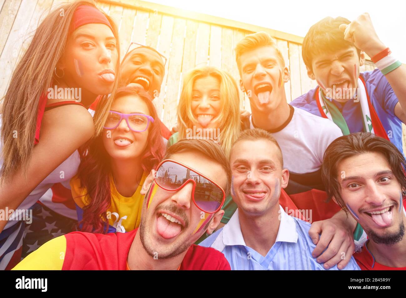 Multinational football supporters taking selfie outdoors - Happy multiracial people making funny faces on camera for olympic games - Sport against rac Stock Photo