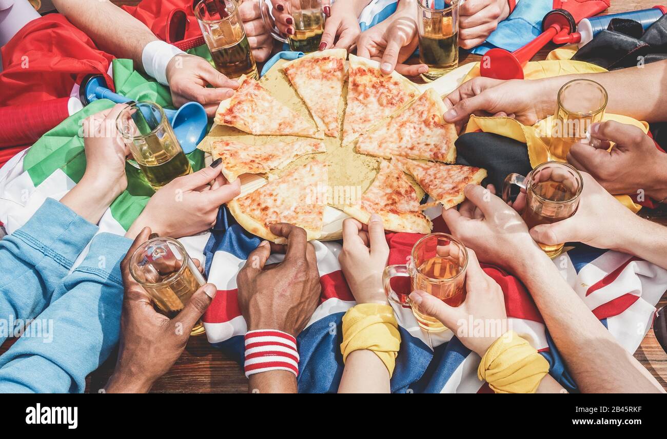 Hands top view of football supporter sharing pizza and drinking half pint beers - Sport fans having fun after game match - Friendship concept with soc Stock Photo