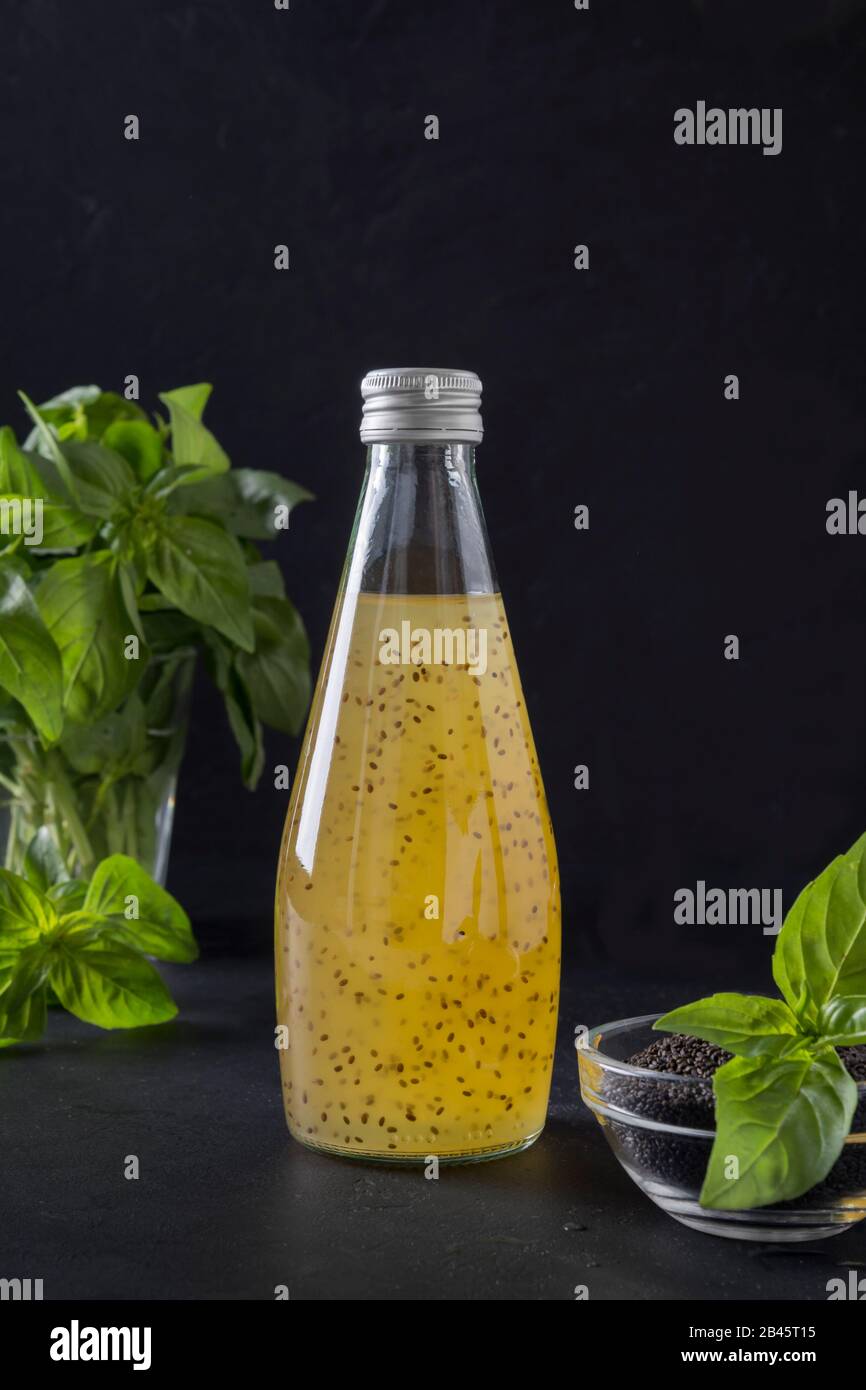 Orange tropical orange juice with basil seeds in bottle on black