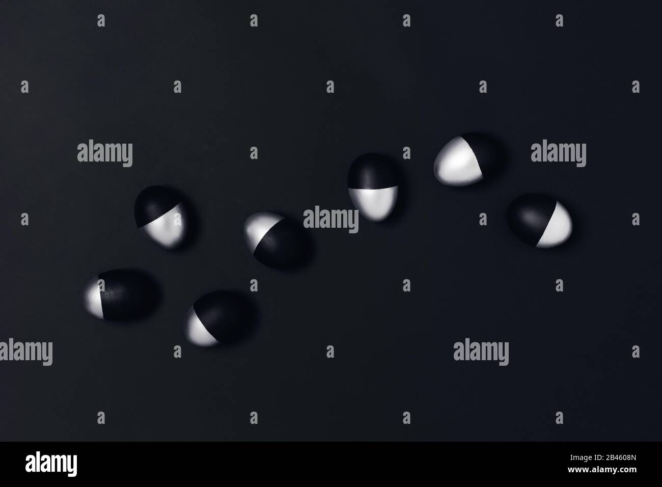 Seven black and silver Easter eggs on dark grey background. Flat lay, top view, copy space. Stock Photo