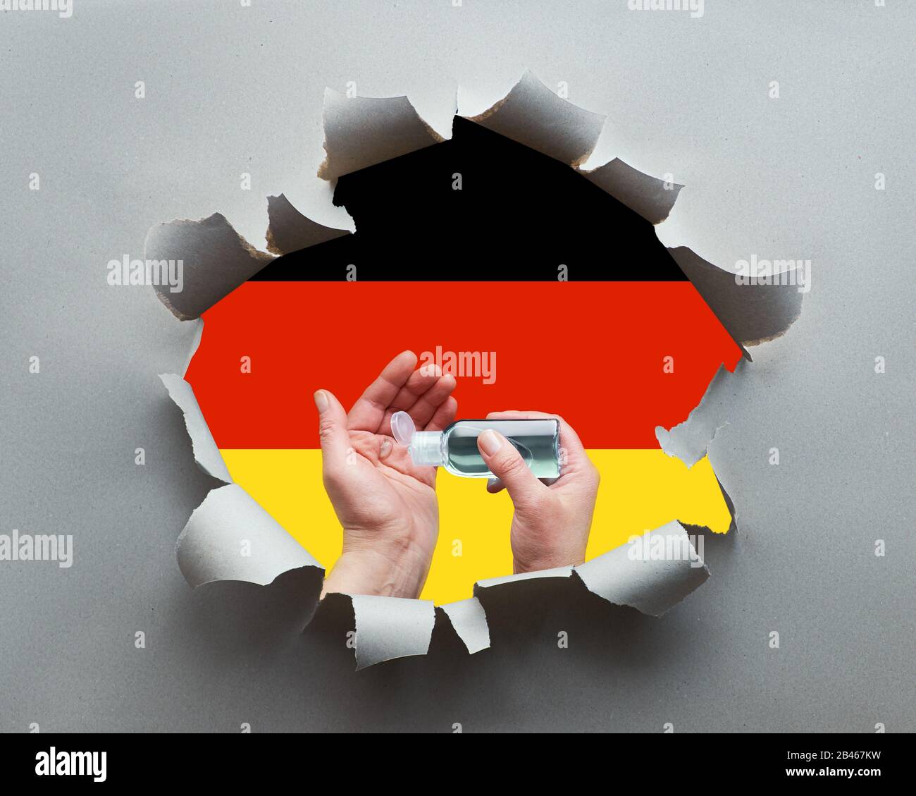 Germany fights against coronavirus. Hand hygiene with disinfection gel in paper hole with German flag as background. Hygiene measures, prevention of p Stock Photo