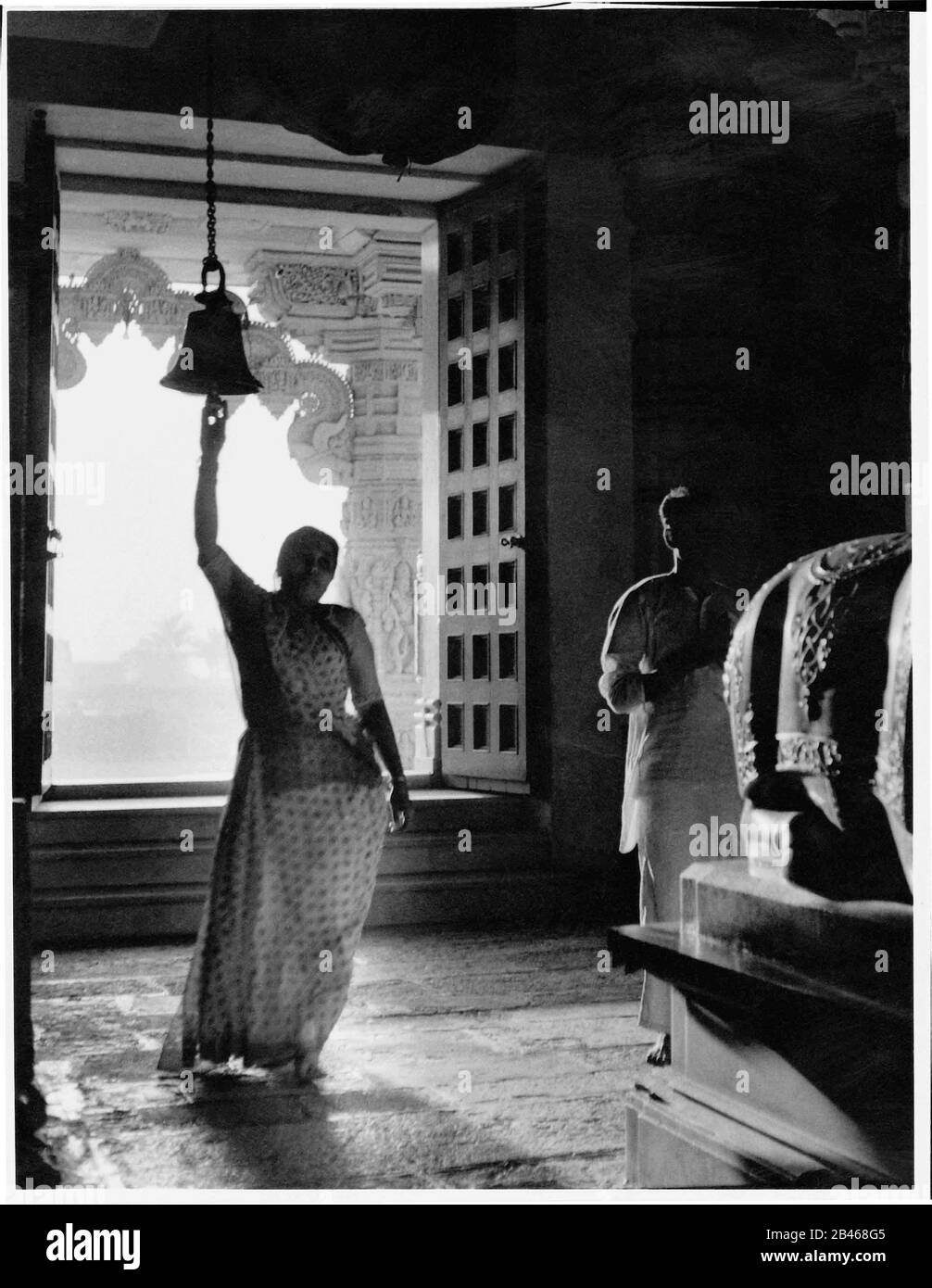 Indian woman ringing temple bell, Somnath Temple, Shree Somnath Jyotirlinga Temple, Prabhas Patan, Veraval, Saurashtra, Gujarat, India, Asia, 1963, old vintage 1900s picture Stock Photo