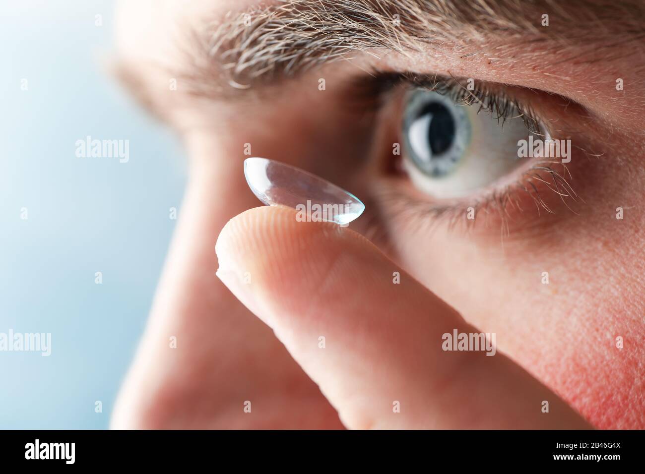 Inserting a corrective contact lens. Man with blue eyes Stock Photo Alamy